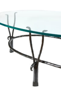 Close up of an oval coffee table designed by garouste Bonetti, legs in black wrought iron and top in glass
