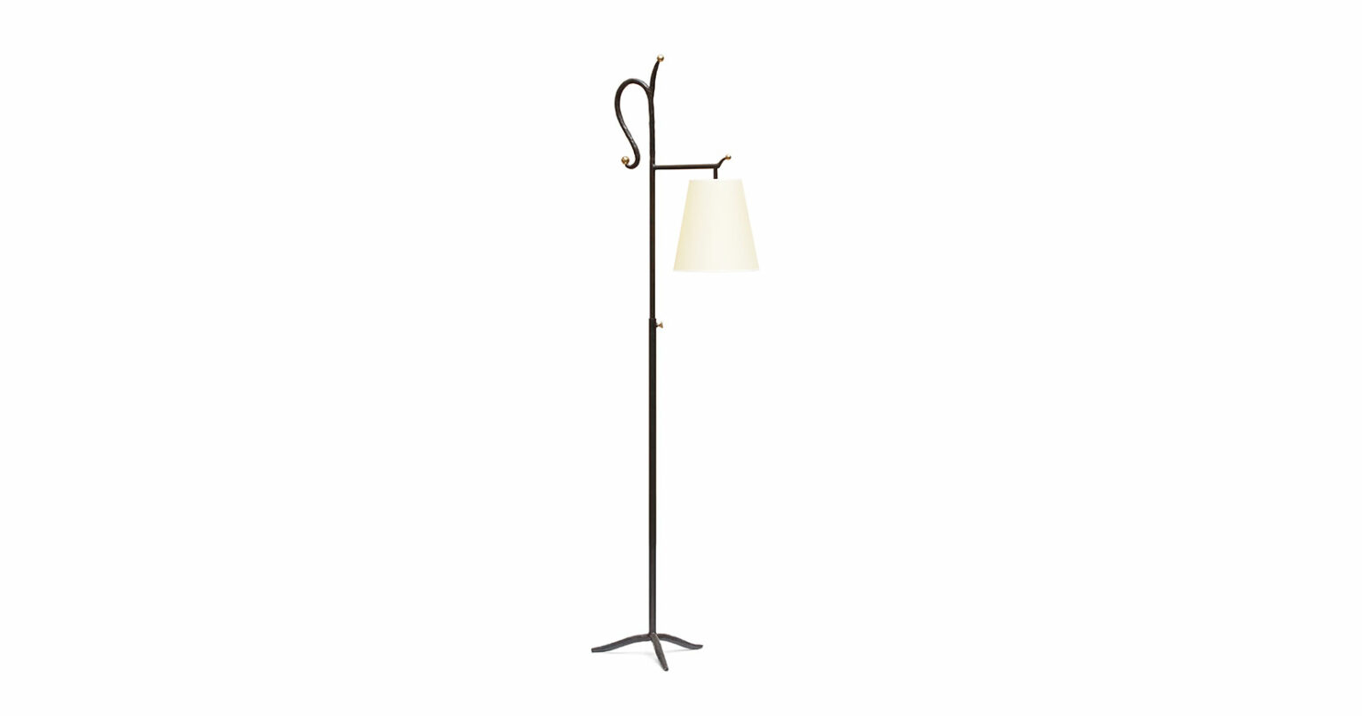 Garouste Bonetti, floor lamp in black wrought iron, 3 flattened curved legs, a straight stem that ends with a baroque curved shape, and a small horizontal rod from which a beige lampshade is suspended,
