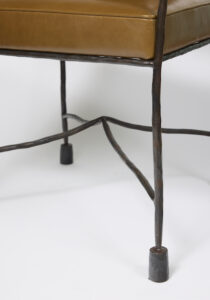 Close up of a Garouste Bonetti armchair, seat in brown leather, legs in brown wrought iron