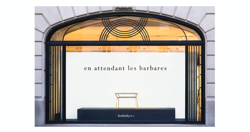Septembre 2026, la table basse Lugano de Mattia Bonetti, présentée dans la vitrine de Sotheby's, pieds en fer forgé recouvert de feuille d'or et plateau en marbre beige, pour l'exposition Garouste ou Bonetti