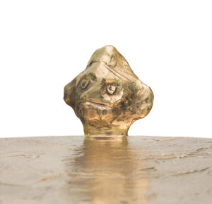 Gros plan du guéridon Golden Him d'Elizabeth Garouste en bronze doré,représentant un visage d'homme, en édition limitée