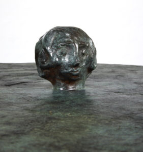 Close up of the side table Her in green bronze by Elizabeth Garouste, face of a smiling woman